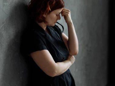 A stressed woman holding her head, symbolizing emotional challenges that EFT can help address.