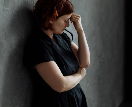 A stressed woman holding her head, symbolizing emotional challenges that EFT can help address.